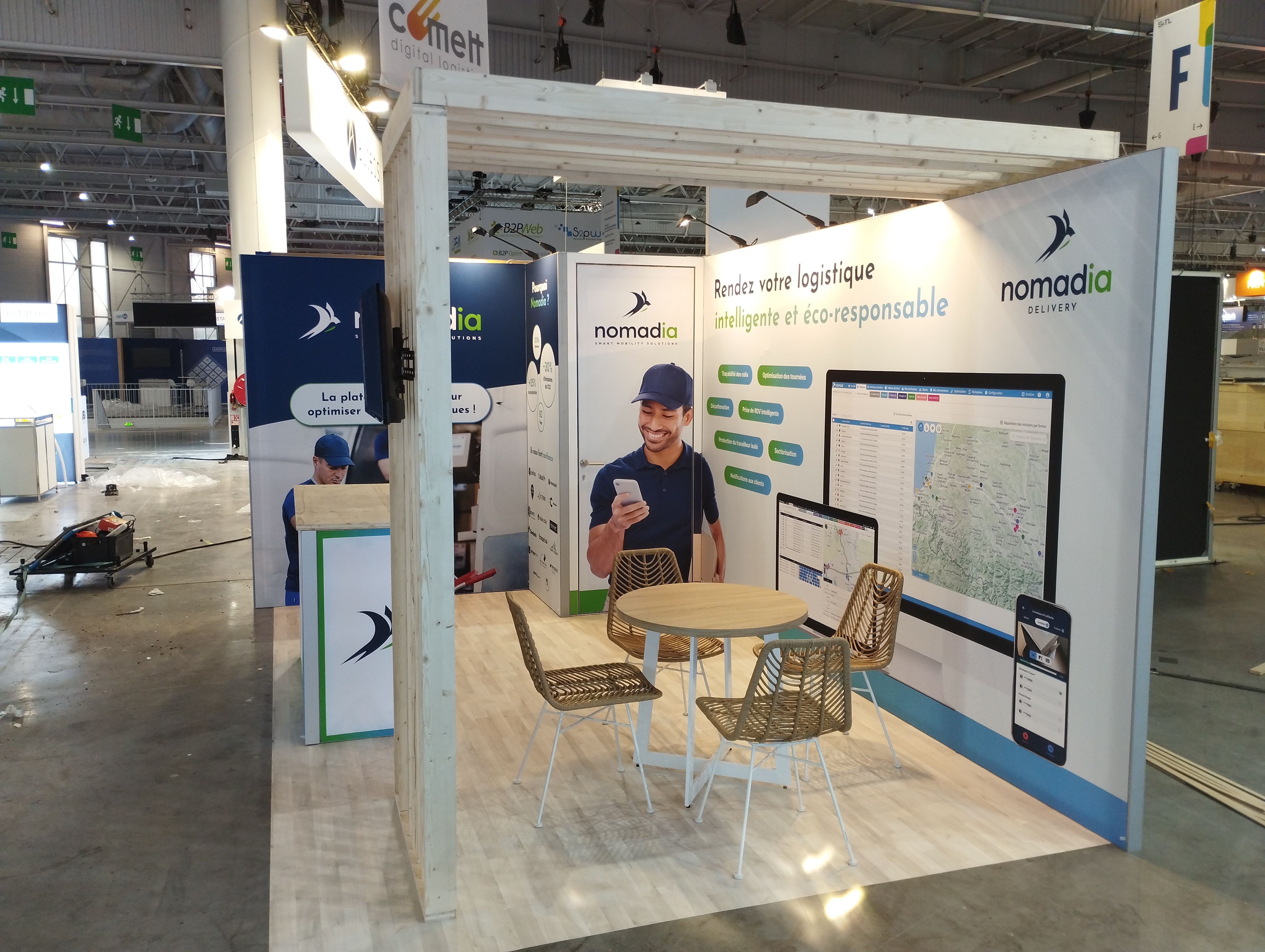 Stand de Nomadia au SITL 2024 à Paris avec claustra en bois et table et chaise en osier.